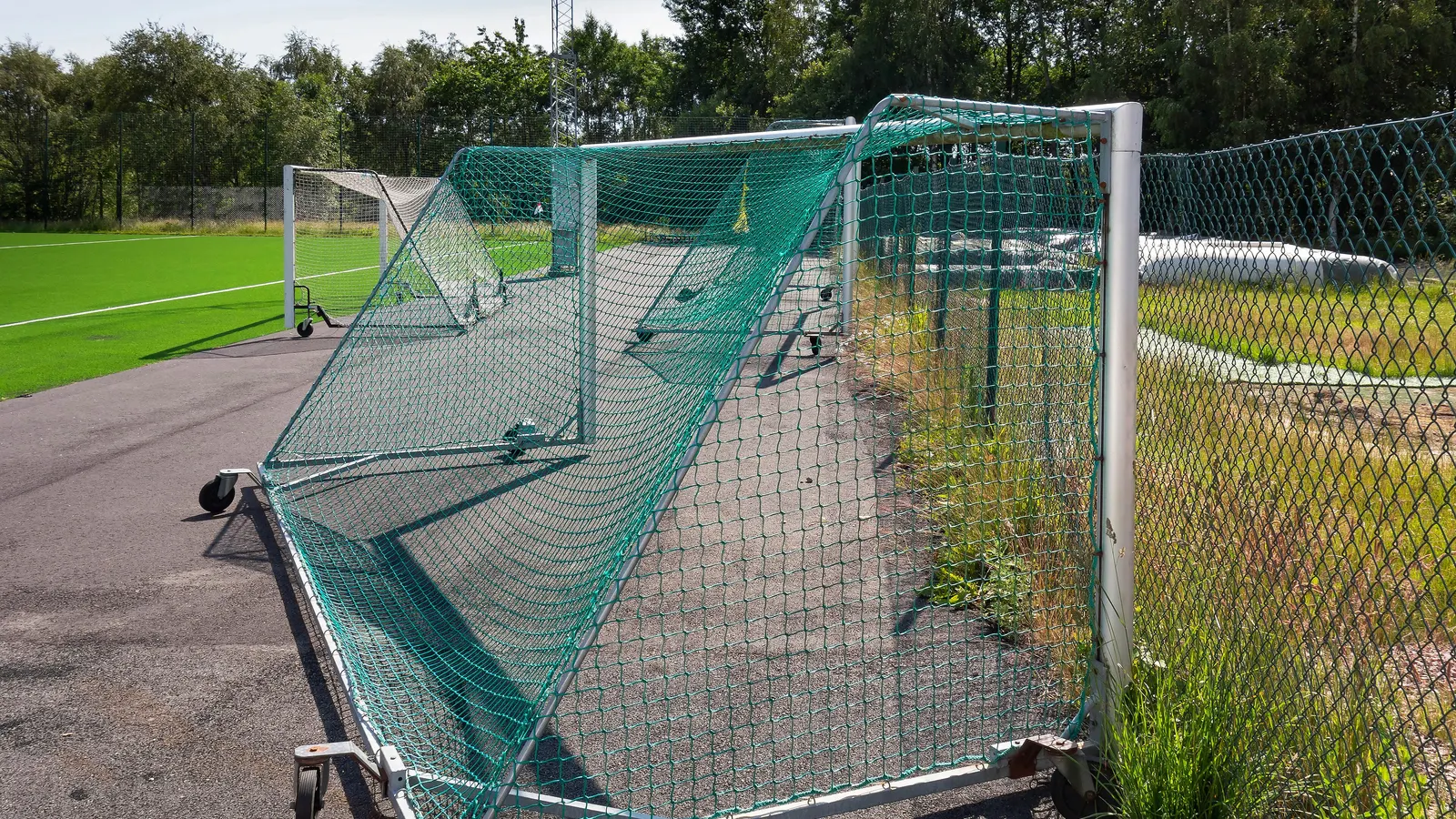 Poteaux de but d'un terrain de football sur une pelouse verte, sous un ciel nuageux